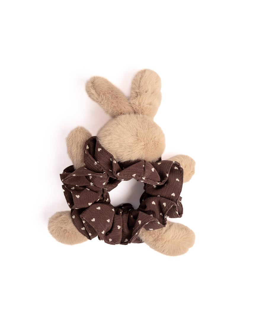 Top view of fluffy brown rabbit hair scrunchie with heart pattern highlighting soft plush bunny ears and voluminous ruffles