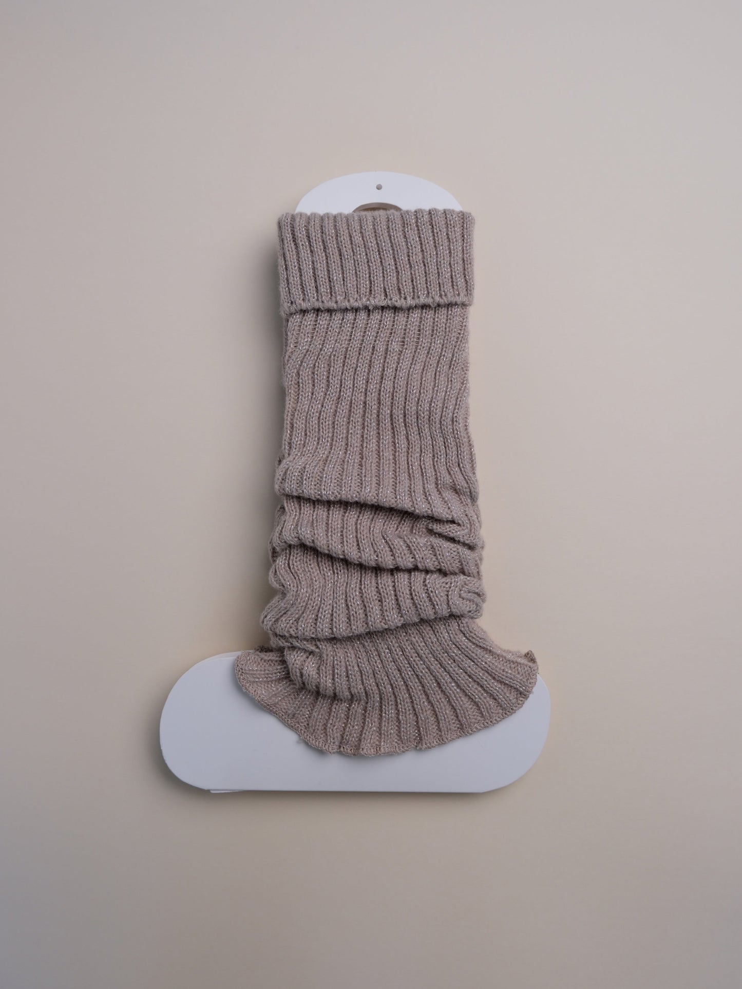 Beige ribbed sock on a white platform against a beige background