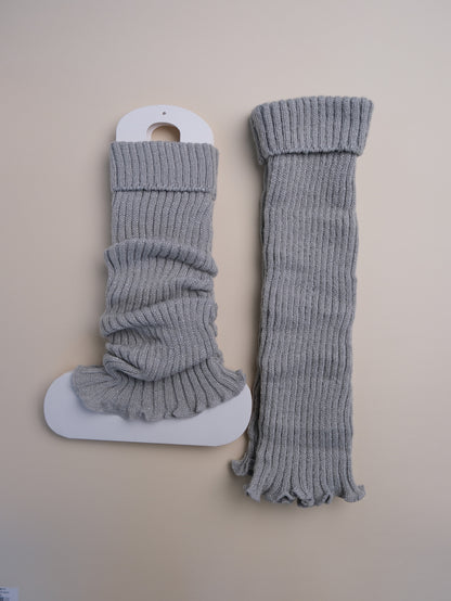 Pair of gray ribbed leg warmers on a beige background