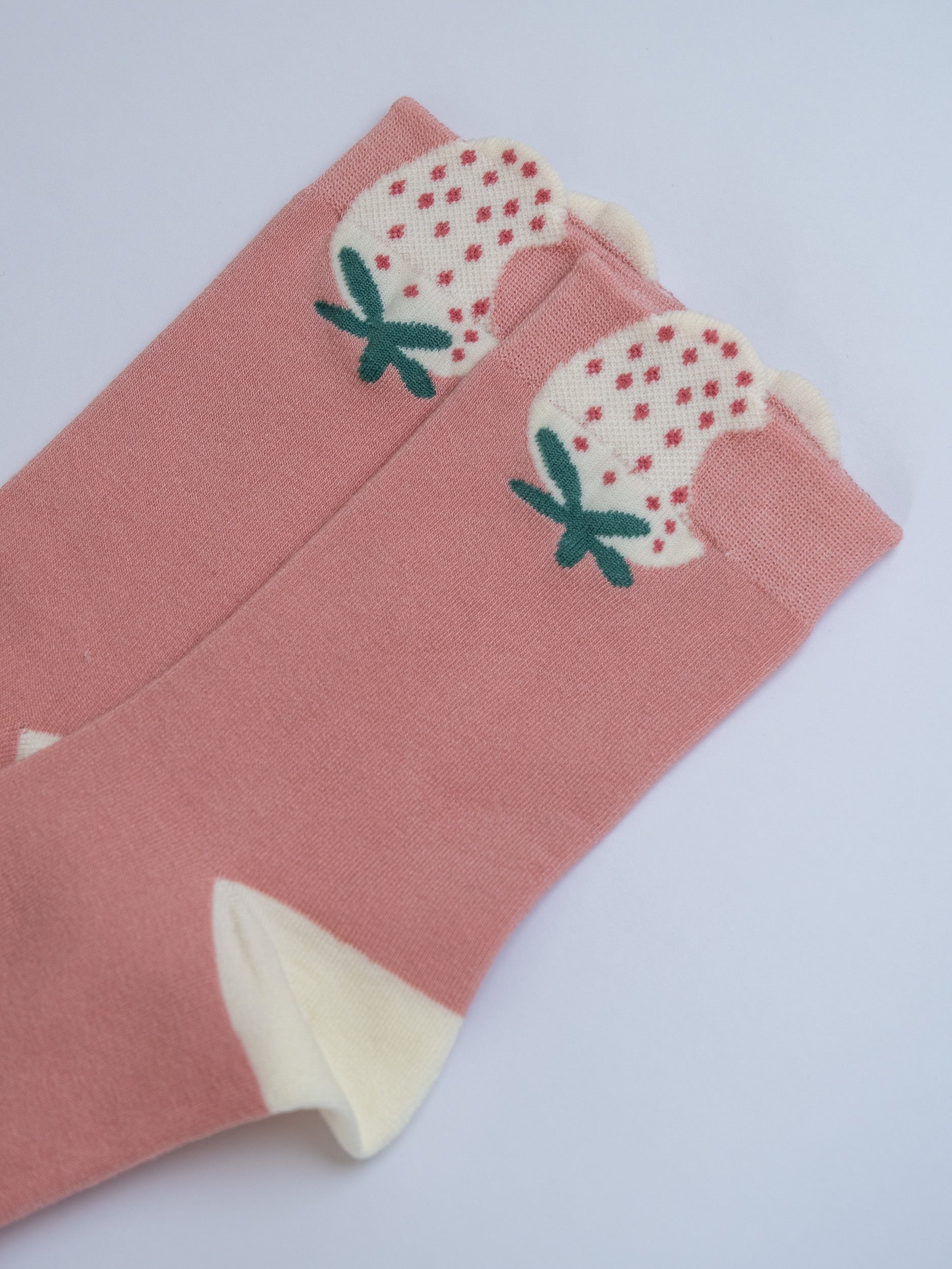 Pink socks with strawberry design on a light gray background