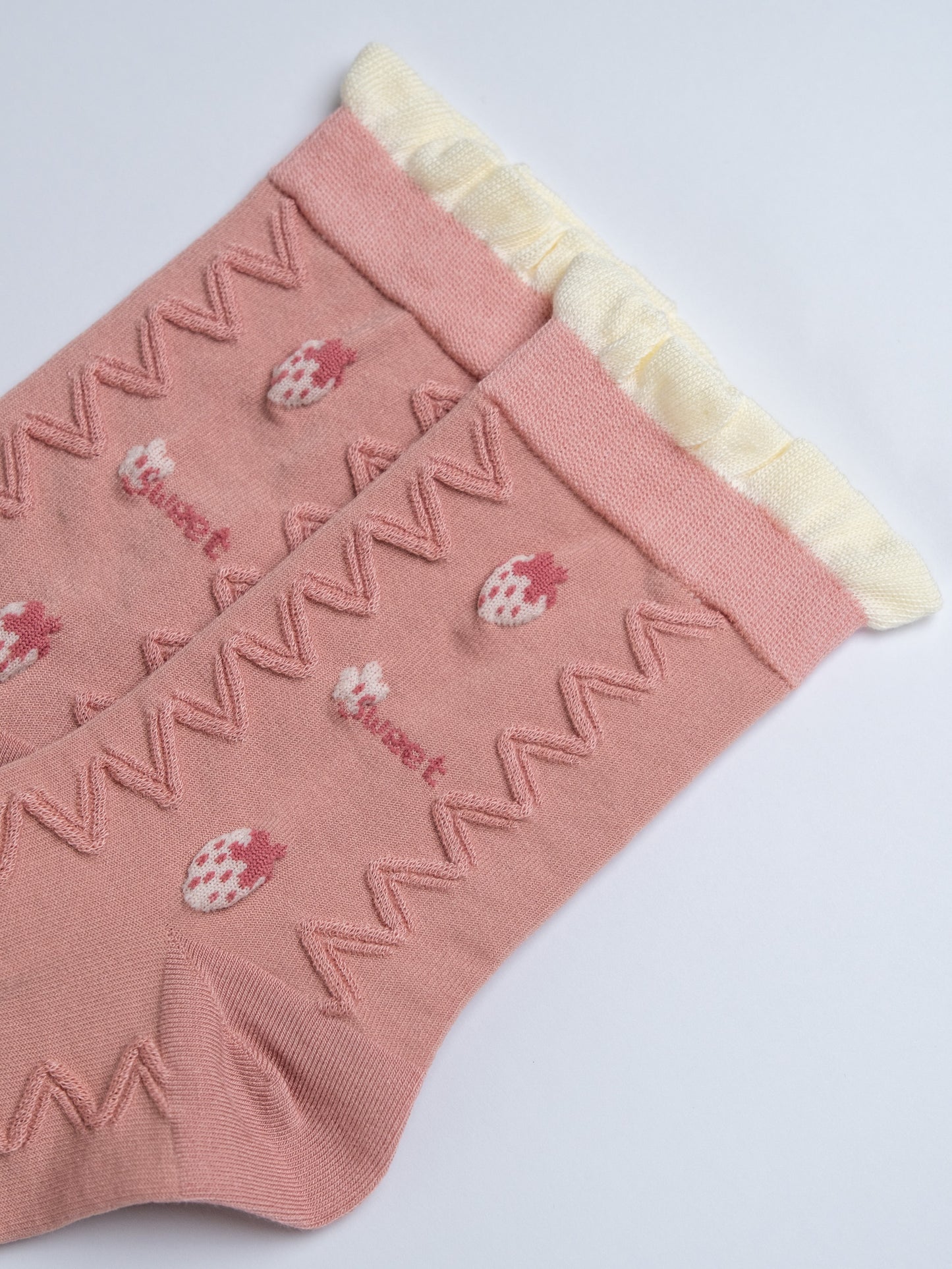 Pink socks with strawberry design and white trim on a light gray background