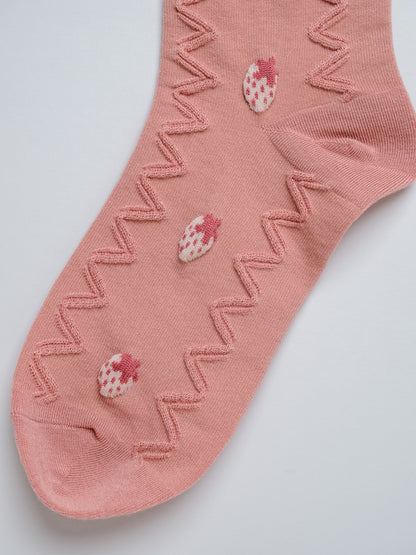 Pink sock with strawberry patterns on a light gray background