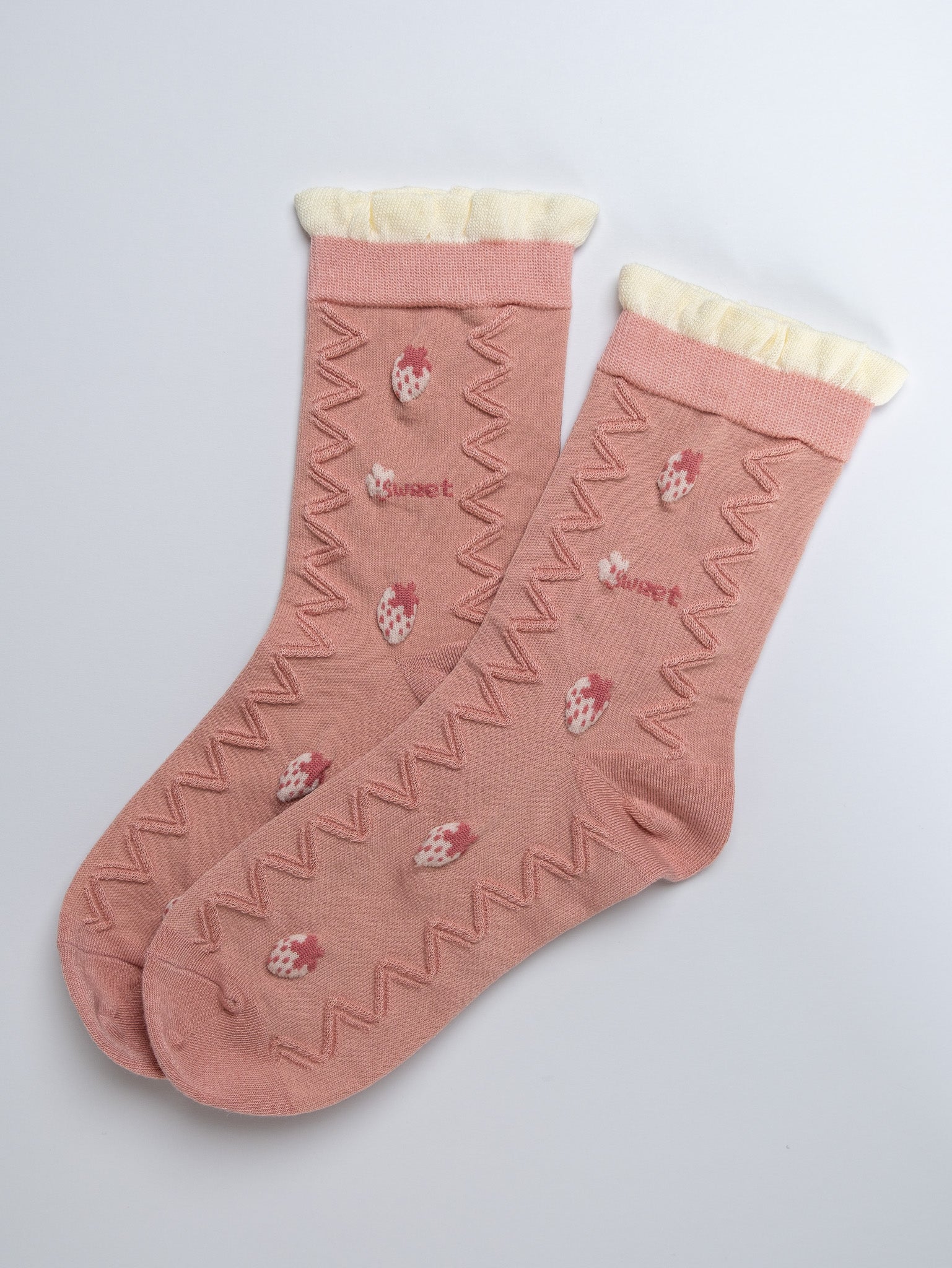 Pair of pink socks with white patterns on a light gray background