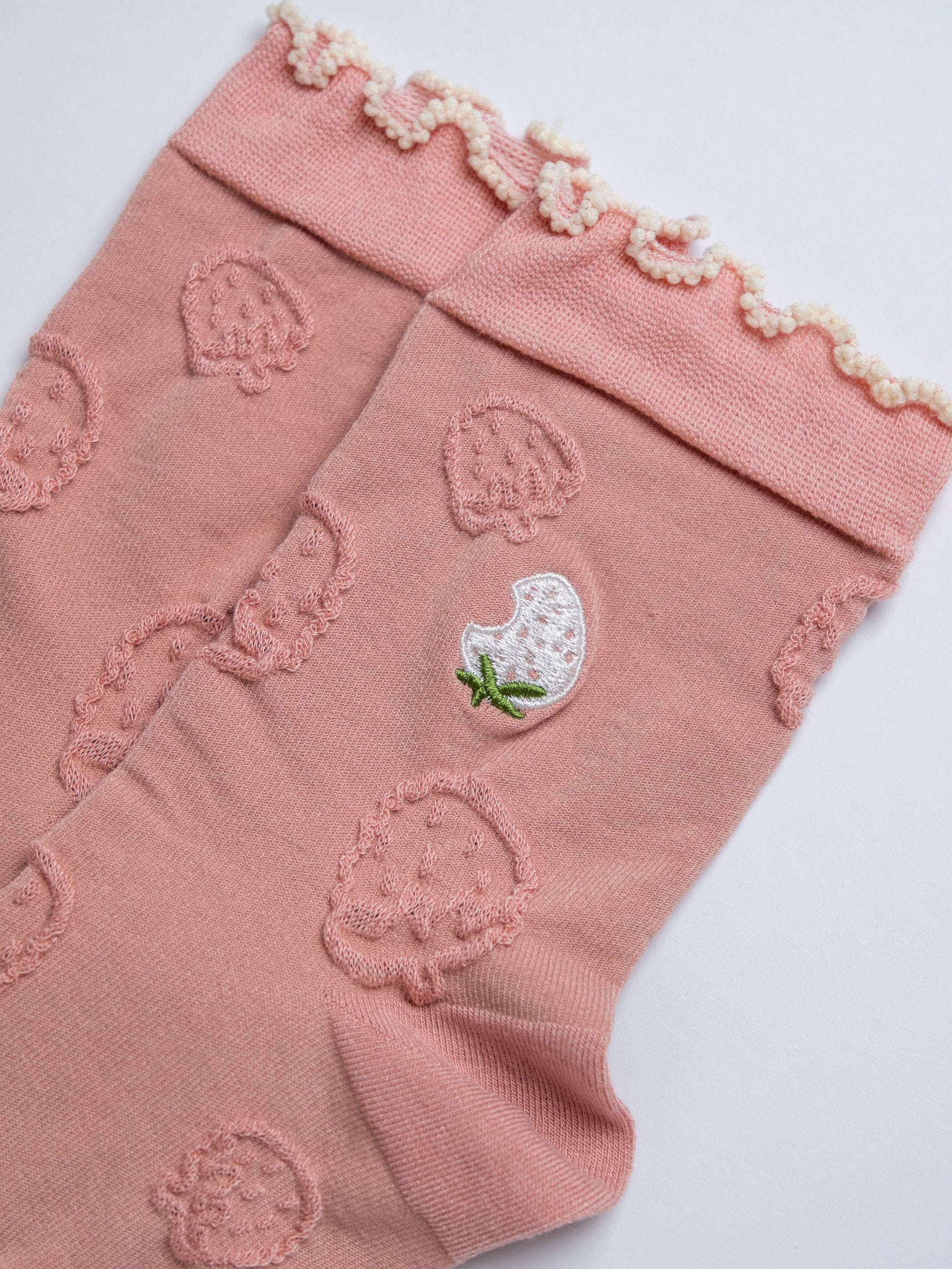 Pink leg warmers with strawberry pattern on a white background