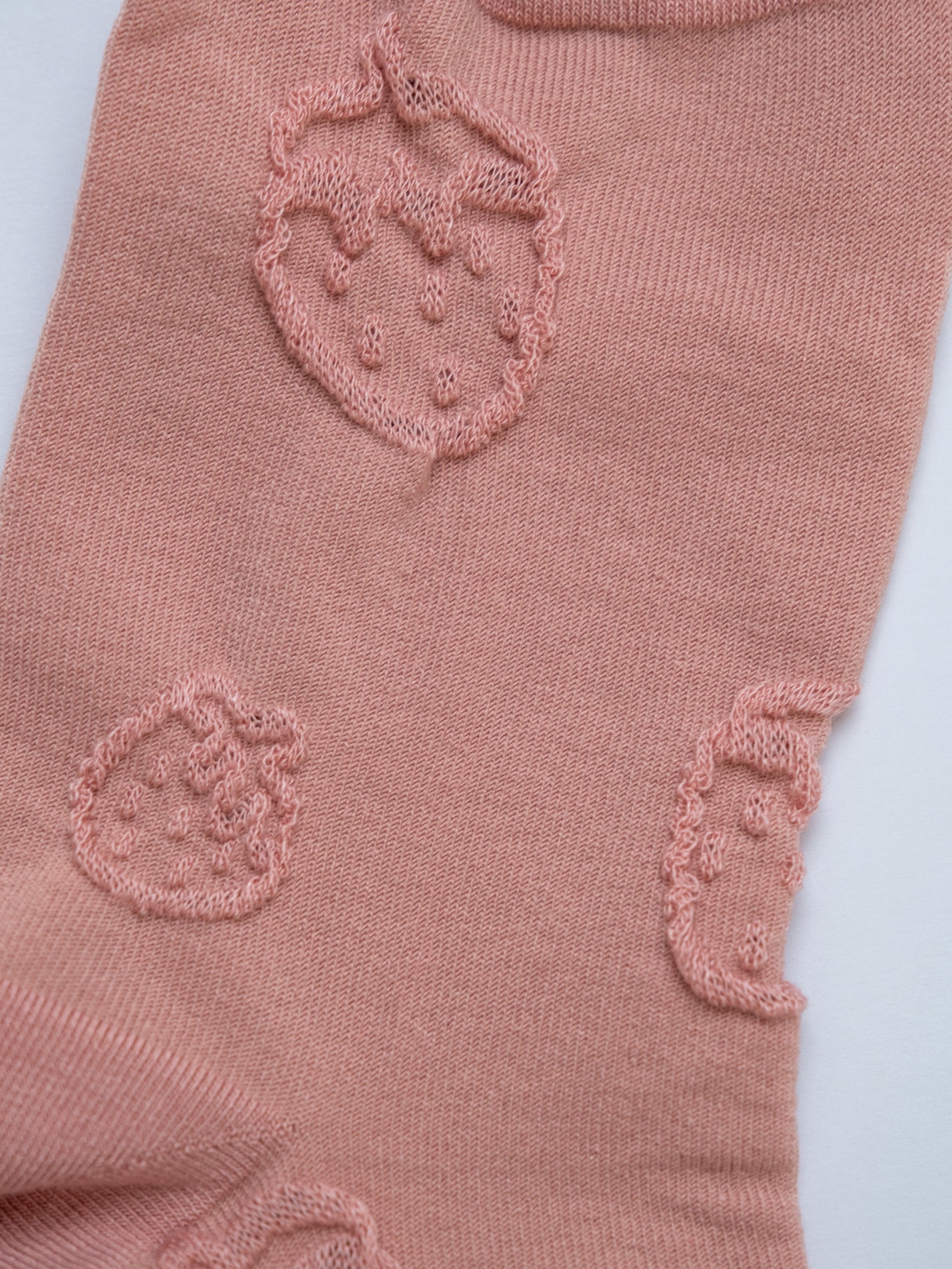 Pink fabric with embroidered designs on a light 