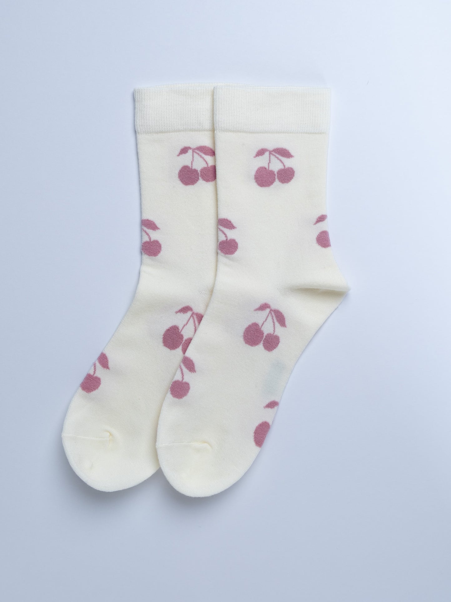 White socks with pink cherry pattern on a light gray background