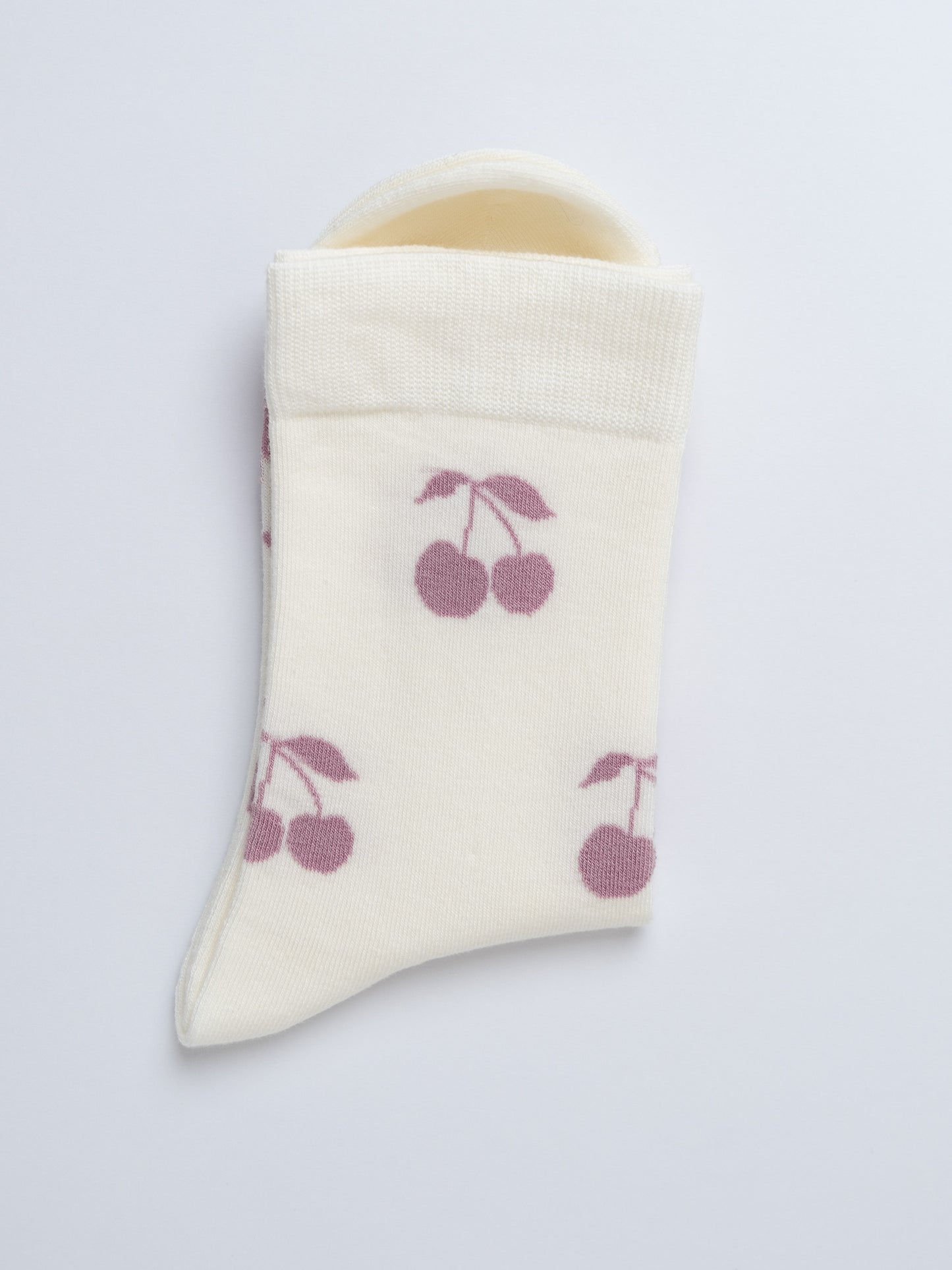 Baby bootie with cherry pattern on a light gray background