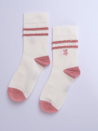 Pair of cream socks with pink accents on a light purple background