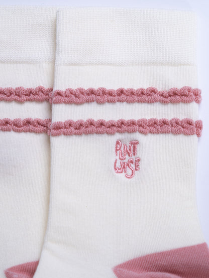 White fabric with pink trim and embroidered text on a white background