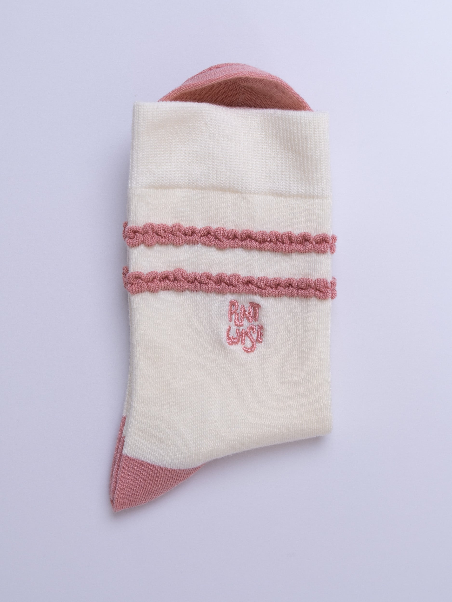 White sock with pink trim and logo on a light purple background
