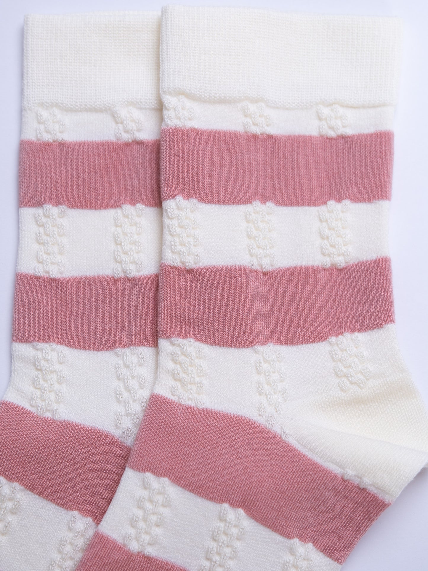 Pair of pink and white striped socks on a light purple background