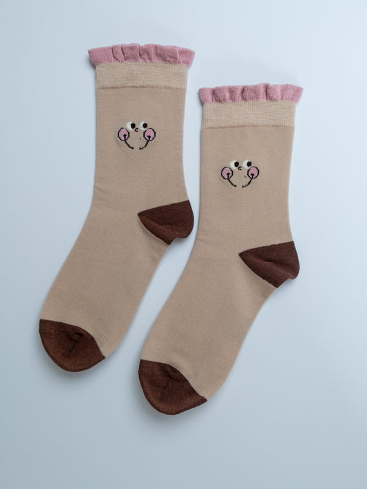 Pair of beige socks with cartoon face design on a light blue background