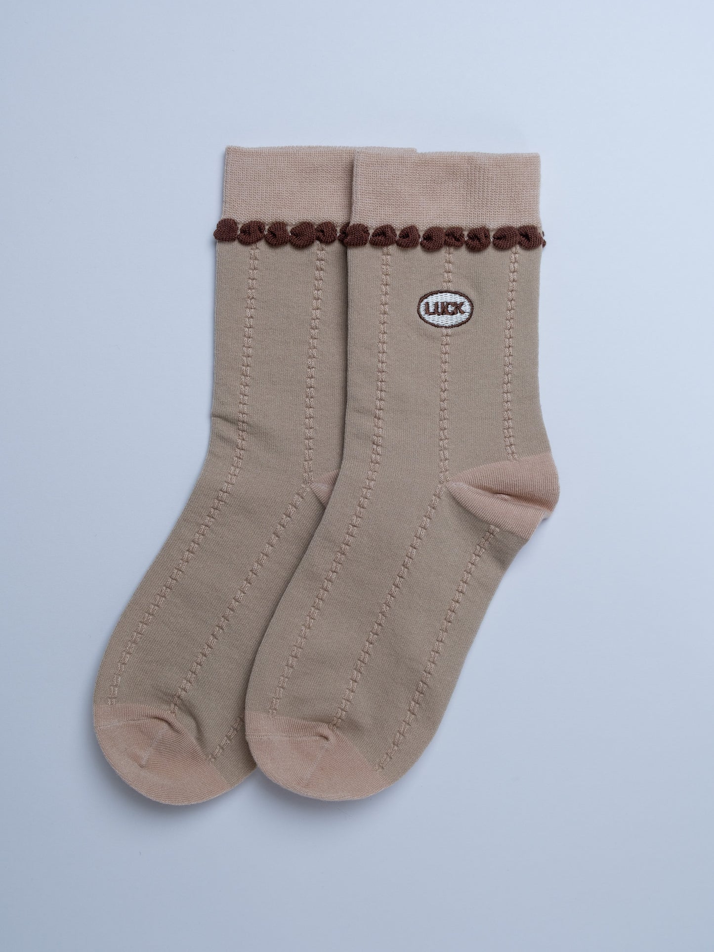 Beige socks with brown decorative elements on a light gray background