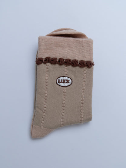 Beige fabric pouch with brown decorative elements and a logo on a light gray background