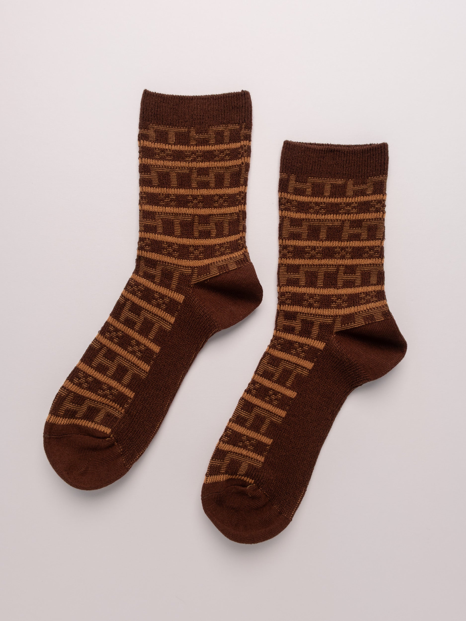 Pair of brown socks with a pattern on a light gray background