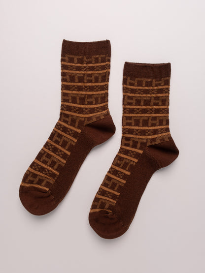 Pair of brown socks with a pattern on a light gray background