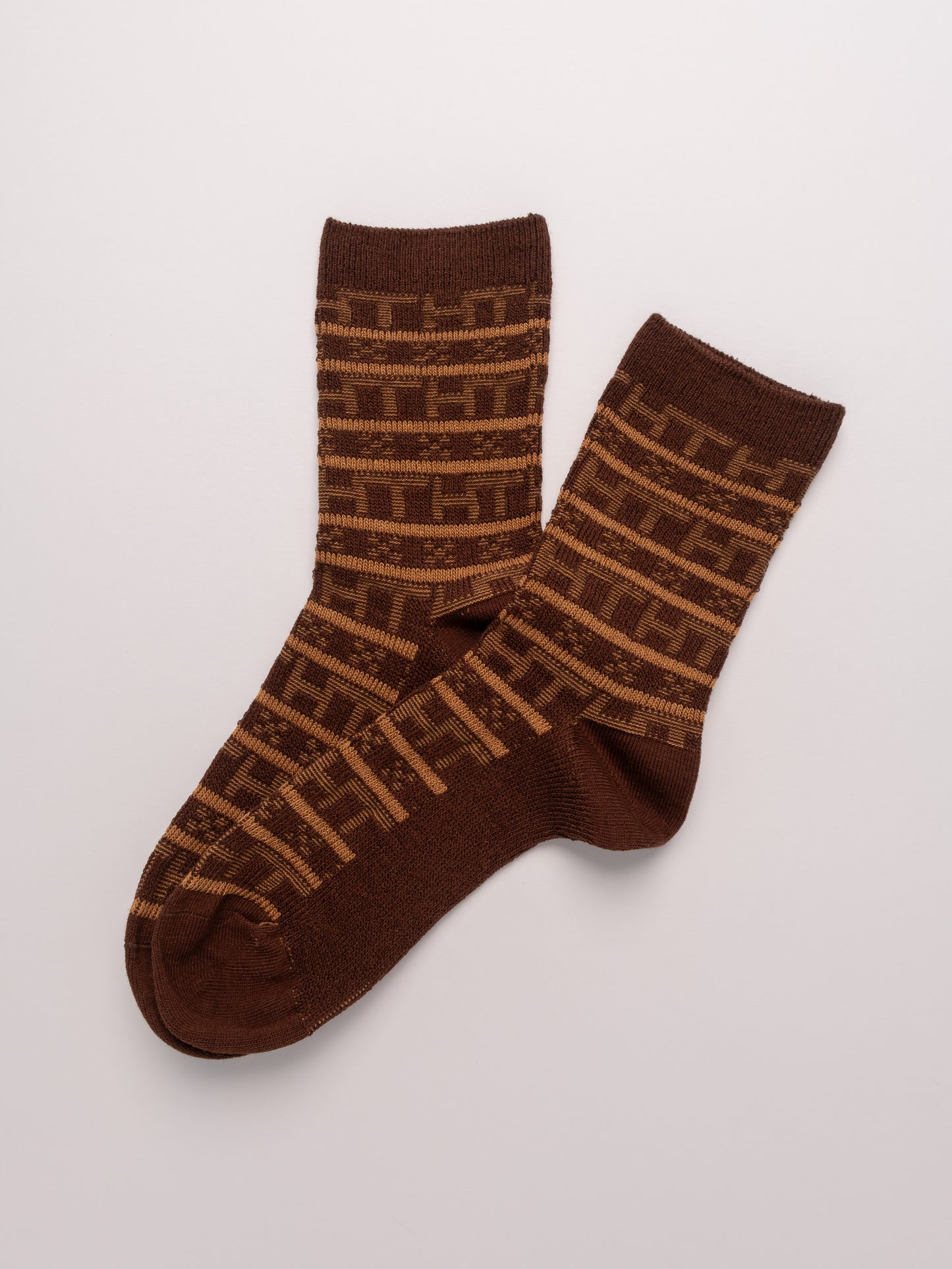 Pair of brown socks with a geometric pattern on a light gray background