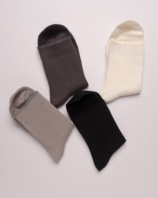 Four pairs of socks in black, gray, and beige on a light gray background