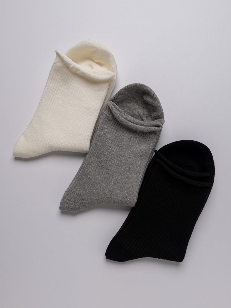 Three pairs of socks in white, gray, and black on a light gray background
