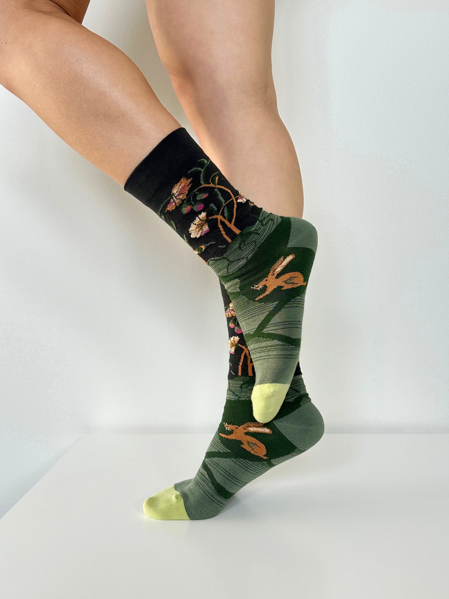 Green socks with nature-themed design worn by a person on a white background